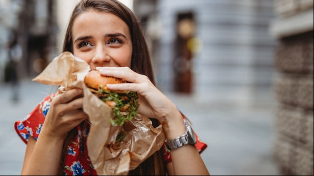 mujer comiendo una hamburguesa en la calle