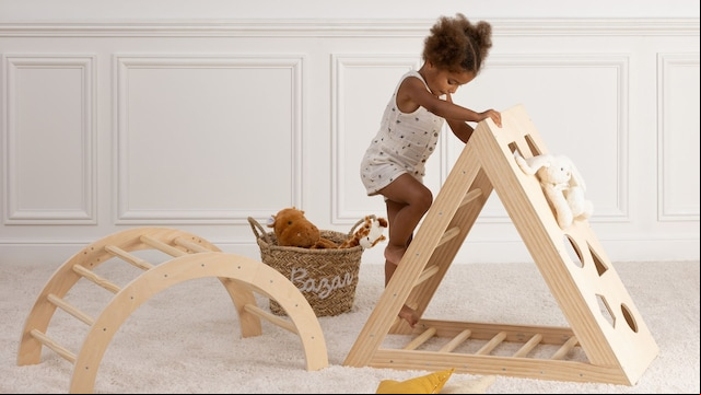 Habitación Montessori con niña jugando en triángulo Pikler
