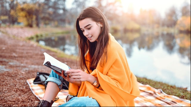 Chica leyendo un libro en el parque en otoño