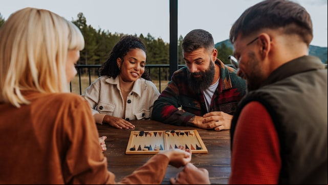 Amigos jugando al backgamon, un juego de mesa, en una escapada en la montaña