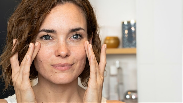 Mujer sonriente aplicándose crema en la cara