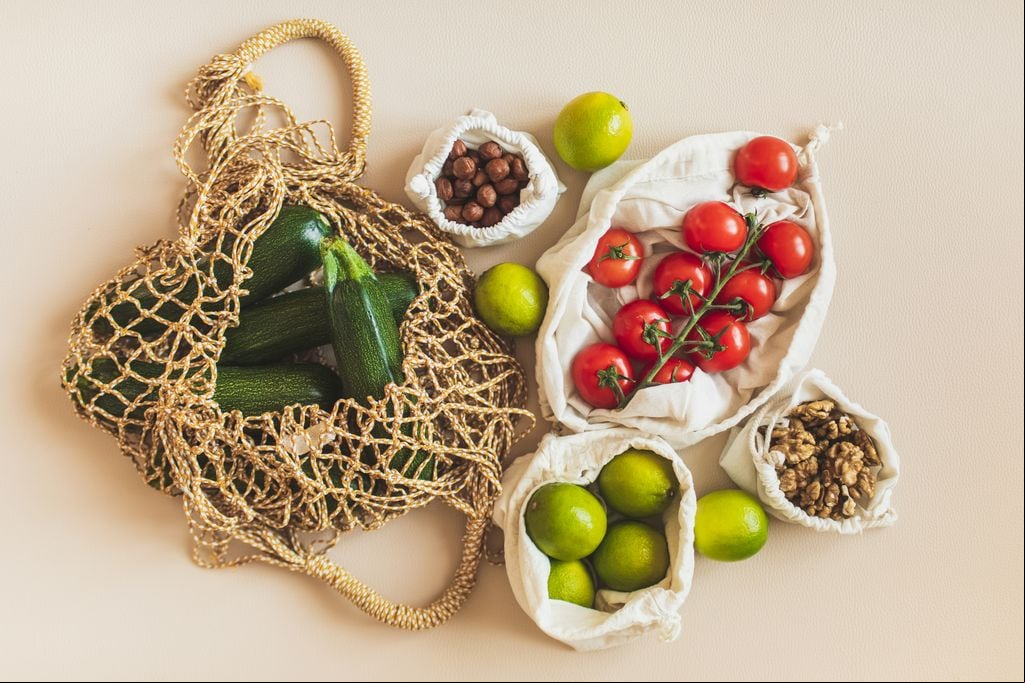 Bolsas de la compra reutilizables con materias primas saludables: tomate, nueces, limas y calabacines