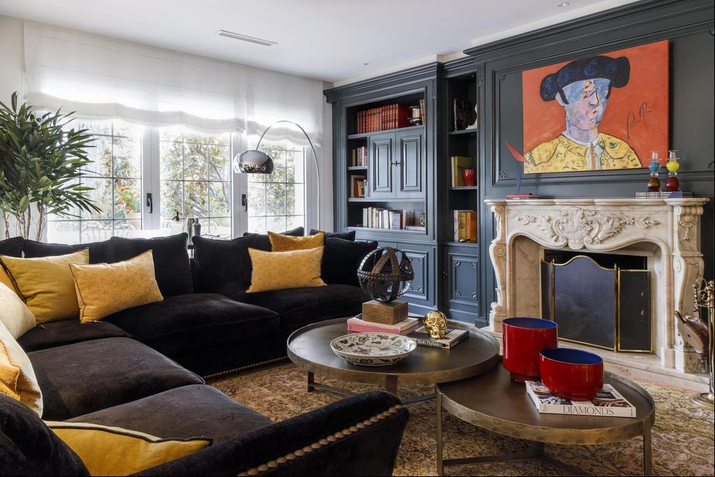 Salón con boiserie pintada y chimenea clásica.