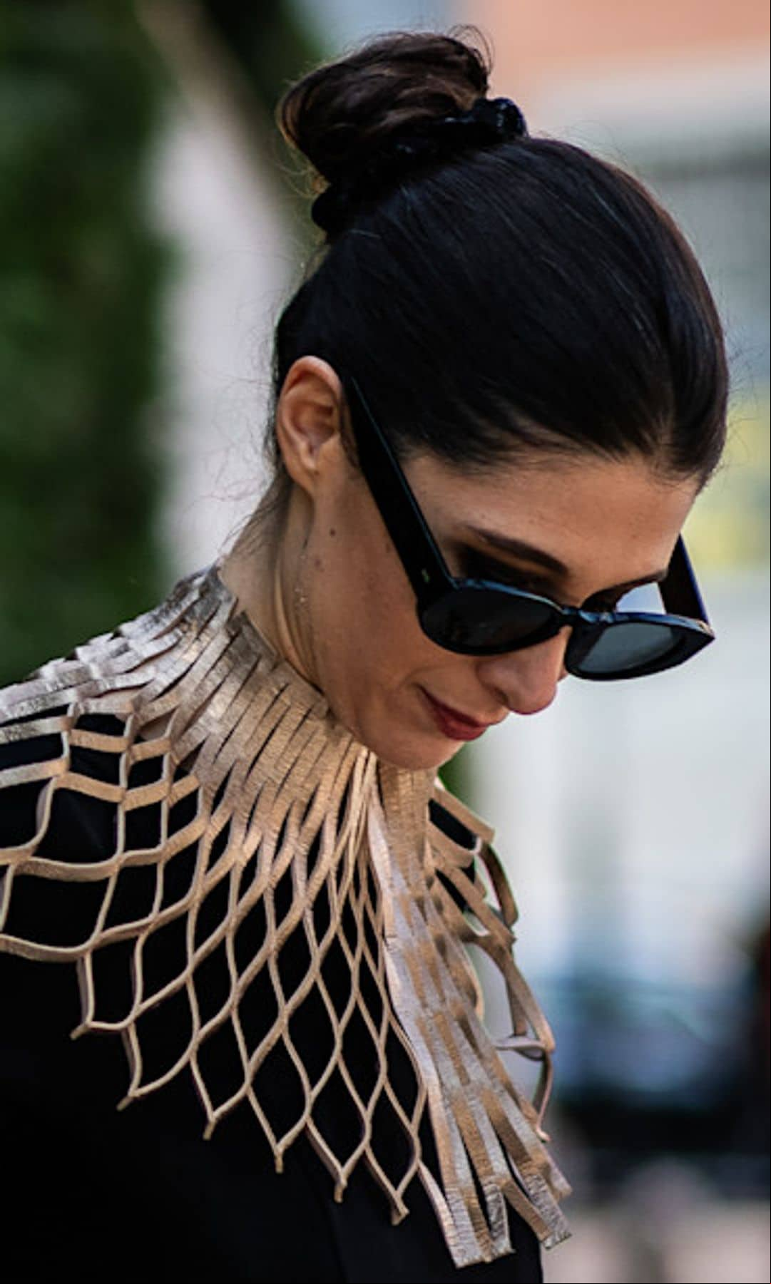 Invitada con vestido negro, moño alto y gafas de sol